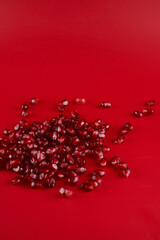 Ruby ripe fresh juicy pomegranate seeds close up isolated on red background