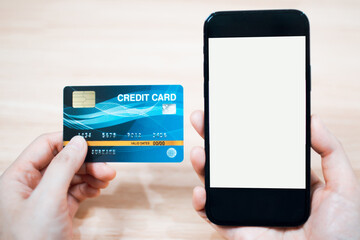 Online payment and shopping concept. Hand holding a credit card and using smartphone with blank screen for online shopping.