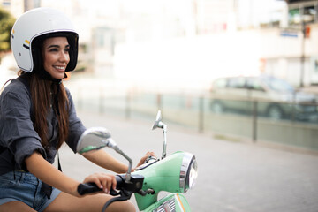 Fototapeta na wymiar Beautiful woman getting ready for a ride on scooter. Beautiful happy lady having fun outdoors