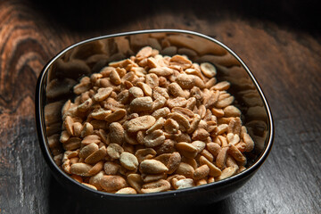 Fried salted peanuts in a deep cup is on the table.