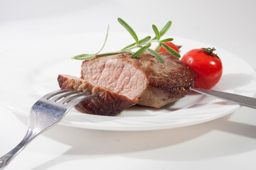 Appetizing steak well done on a white plate with tomatoes and rosemary