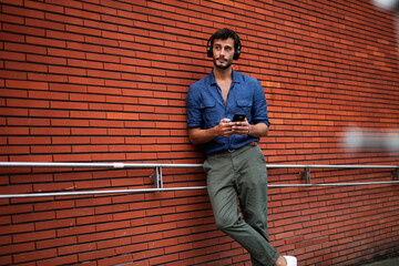 Fototapeta na wymiar Young man listening to music. Urban fashion man with headphones enjoying the city.