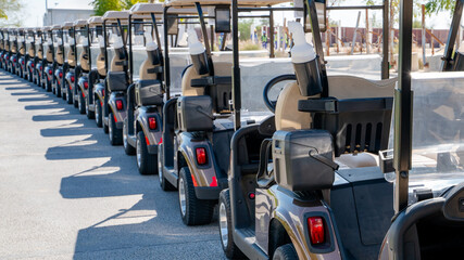 A row of electric golf carts on a golf course.