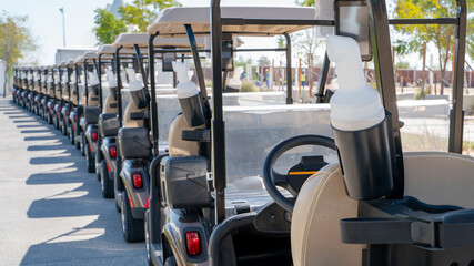 Fototapeta na wymiar A row of electric golf carts on a golf course.