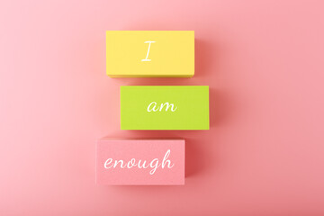 I am enough concept with words written on colorful rectangles against bright pink background