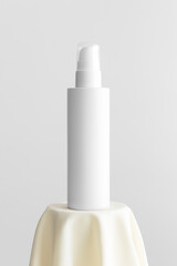 White cosmetic lotion bottle mockup on the yellow textile.