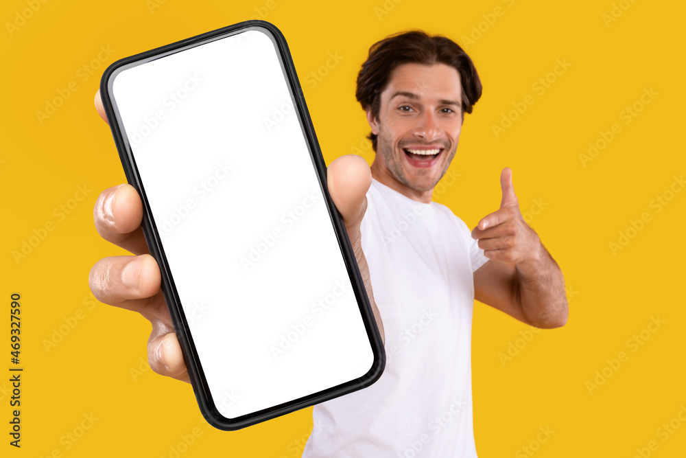 Poster cheerful man pointing at white empty smartphone screen