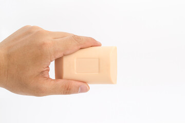 Asian mand hand holds rectangle cream color soap in studio light on white clear background.