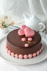 Chocolate cake with chocolate frosting and pink heart decoration on the table