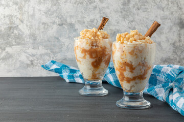 Two glasses with rice pudding dessert on a table with a blue tablecloth