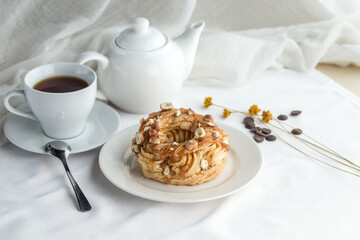 Caramel nut choux pastry Rings with Cream Filling and cup of tea on the table