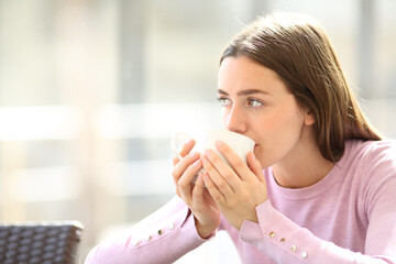 Distracted woman drinking coffee in a restaurant