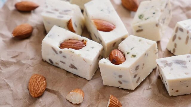 Walnut halva with almonds and sunflower seeds on brown craft paper. Traditional oriental dessert.