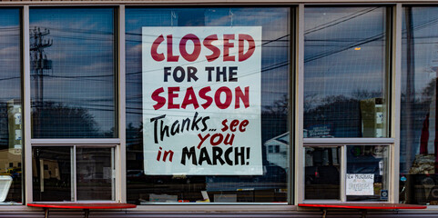 Fototapeta na wymiar A Closed for the season sign in the window of an ice cream shop in Binghamton in Broome County in Upstate NY. 