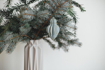 Christmas ornament on fir branch close up. Modern vintage wooden bauble. Merry Christmas!