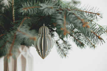 Stylish christmas ornament on fir branch close up. Vintage wooden bauble. Merry Christmas!