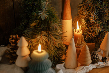 Stylish burning christmas candles, pine trees, cones on rustic background in evening.Merry Christmas