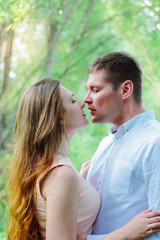 Young lovely couple kiss each other behind the trees