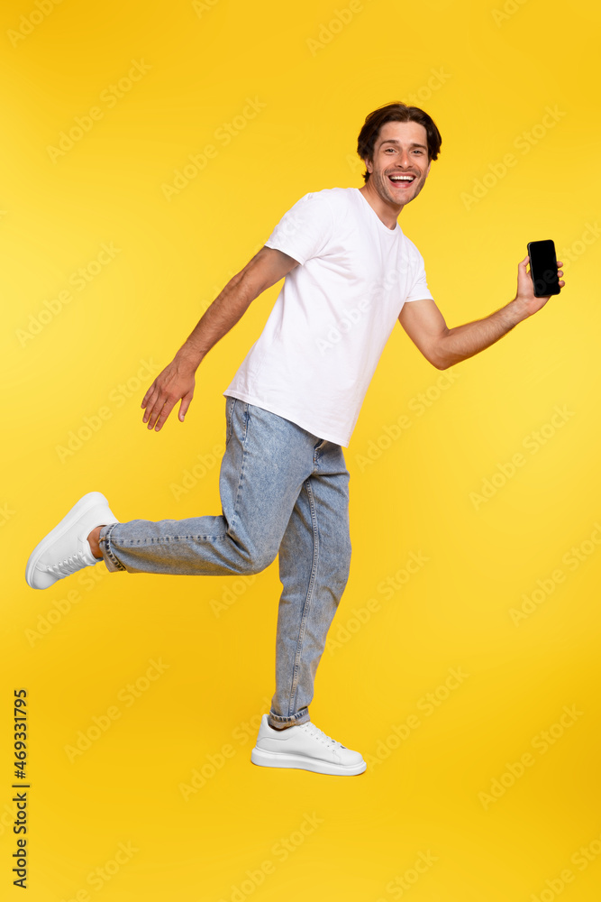 Poster Man showing white empty smartphone screen and jumping up high