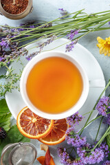 A cup of organic tea with dry fruit, flowers, and herbs, shot from above. Healthy hot drink