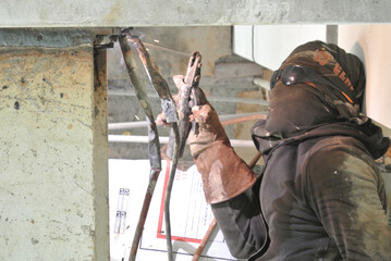 SELANGOR, MALAYSIA -DECEMBER 09, 2015: Welder wearing protective mask welding metal at the construction site. 