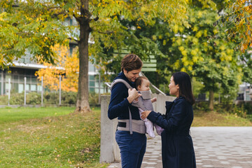 Naklejka premium Woman Adjusting Baby Carrier On Man With Daughter