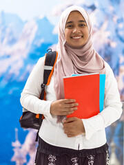 a portrait of a happy Middle Eastern university student in front of a snowy mountain in the background