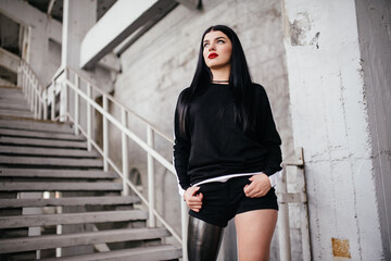 Beautiful girl with a prosthetic leg posing on the street. - obrazy, fototapety, plakaty