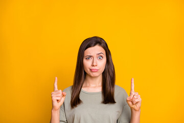 Portrait of lovely confused skeptic brown-haired girl demonstrating up copy empty place space isolated over bright yellow color background