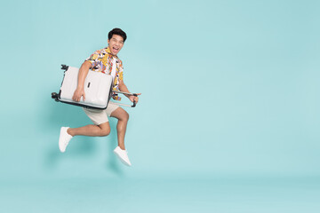 Happy Young Asian traveler man jumping with suitcase bag isolated on green background, Tourist in...