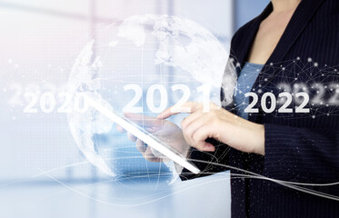 New year concept- hand touch white tablet with digital hologram 2021 sign on light blurred background - 2022 new year.