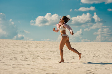 Naklejka premium Happy middle aged woman running on sandy beach