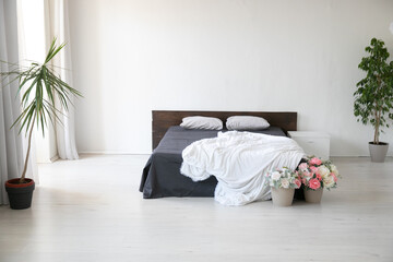 interior of a white bedroom with a bed and plants with flowers