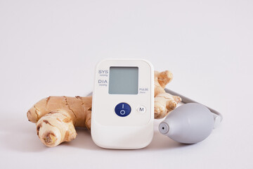 blood pressure monitor and ginger root on gray background