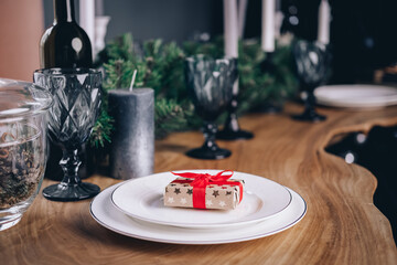 Festive table setting for Christmas or New Year's dinner with family and friends. gift box with a red bow on a plate