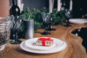 Festive table setting for Christmas or New Year's dinner with family and friends. gift box with a...