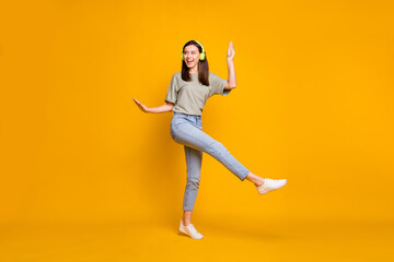 Fototapeta na wymiar Full length photo of young funny funky woman wear headphones dance raise hands isolated on yellow color background