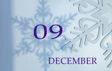 Calendar for December 9: the name of the month in English, number 09 on a blue background of snowflakes and shadows from them.