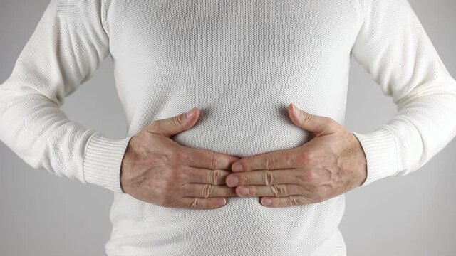 A man gropes himself with pain in his belly