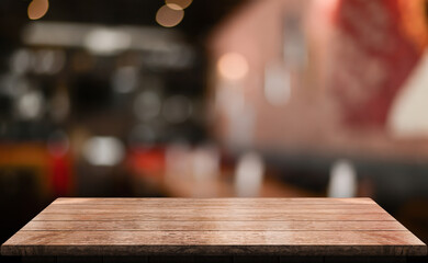Empty wooden table top with lights bokeh on blur restaurant background.