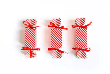 Fototapeta premium Overhead view of 3 unopened striped Christmas crackers, isolated on a white background, copy space.