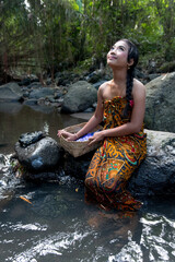 Beautiful Asian Girl with dark hair washing clothes alone the river.