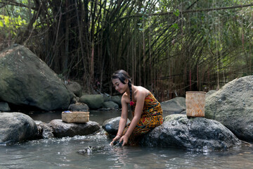 Beautiful Asian Girl with dark hair washing clothes alone the river.