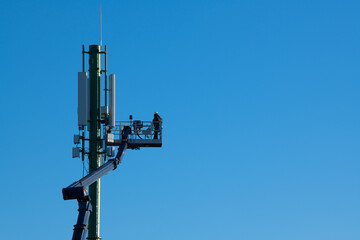 Telecommunications tower with 4G, 5G transmitters, Worker on cellular base station