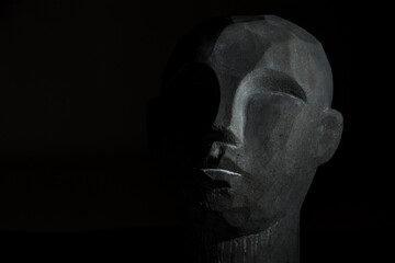 portret kamiennej głowy na czarnym tle, twarz częściowo oświetlona - obrazy, fototapety, plakaty