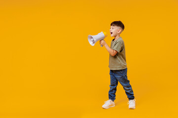 Full body little small smiling happy boy 6-7 years old in green t-shirt hold scream in megaphone...