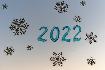 Christmas home window decoration with white snowflakes stickers and handwritten inscription 2022 in blue paint