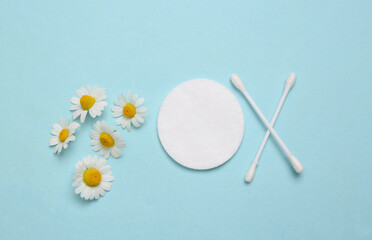 Body care, hygiene. Cotton pads, sticks on a blue background with chamomile flowers