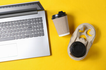 Laptop with Two cardboard coffee cups on yellow background. Top view