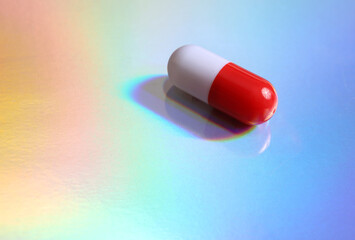 Pill on colored reflective holographic surface